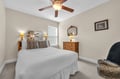 Relax in your serene bedroom with crisp white linens, stylish leopard accents, and a gentle ceiling fan creating perfect comfort.
