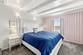Sink into your plush bed beneath an elegant coffered ceiling and let soft lighting ease you into a restful evening. Charming wallpaper and thoughtful details create a cozy, welcoming retreat.