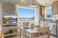 Picture yourself enjoying morning coffee at this charming dining table, where ocean breezes and stunning sea views pour through expansive windows. The cozy coastal kitchen invites relaxed meals and cherished moments.