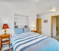 Your bright, serene bedroom awaits with crisp linens, charming nautical stripes, and warm wood accents. Rest easy in this peaceful retreat—everything you need for a cozy night's sleep.