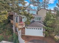 Multi-level coastal home nestled among mature trees with garage and deck space in a peaceful wooded neighborhood.