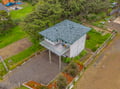 Elevated vacation home nestled among evergreens and lush lawn, featuring covered deck and driveway parking in a tranquil wooded neighborhood.