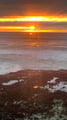A dramatic sunset paints the ocean in brilliant orange and gold hues, creating a stunning coastal display from this oceanfront location.