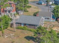 Aerial view of a charming coastal cottage nestled among mature trees in a quiet residential neighborhood.