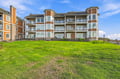 Modern multi-story property featuring contemporary architecture with spacious balconies, surrounded by a lush, expansive green lawn perfect for relaxing outdoors.