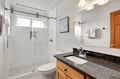 Step into your pristine private bathroom with gleaming marble countertops, spacious glass shower, and plush white towels awaiting your relaxing retreat.