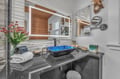 Refresh in your stylish bathroom featuring a striking blue vessel sink, granite countertop, and modern amenities.