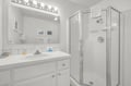 A bright, spotless bathroom with classic subway tile, a roomy glass-enclosed shower, and a well-lit vanity ready for your morning routine.