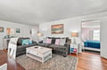 Relax in this cozy living space featuring soft velvet sofas, warm wood floors, and coastal touches throughout. Light pours through the window, creating a bright, welcoming retreat perfect for your seaside getaway.