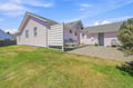 Charming pink coastal cottage with a sunny lawn and private patio, perfect for gathering outdoors or parking with ease.