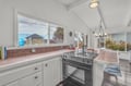 You'll love cooking in this bright, airy kitchen with its charming white beadboard ceiling, warm tile counters, and inspiring neighborhood views through large windows.