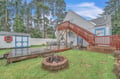 Charming vacation rental featuring spacious deck, outdoor dining area, fire pit for evening gatherings, and private yard surrounded by towering trees.