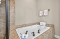 Sink into the deep soaking tub with elegant travertine surround, where plush towels and premium amenities await your relaxing bath time.