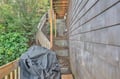 The property features natural wood siding and a protected BBQ area surrounded by lush greenery.