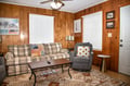 Curl up in your cozy living room with warm wood paneling, plush seating, and natural light streaming through the windows—perfect for relaxing after a day of adventure.