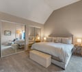 Sink into plush bedding in your serene bedroom retreat, where vaulted ceilings and soft lighting create a calm, restful atmosphere for your perfect night's sleep.
