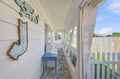 The property's welcoming entrance features a charming covered porch with coastal-themed signage and natural light—the perfect spot to begin your beach vacation.