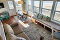Sunlight streams through floor-to-ceiling windows overlooking the beach, filling your open living and dining space with coastal charm and easy access to the sand.