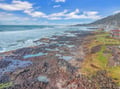 Dramatic rocky coastline with tide pools stretches along this oceanfront community, featuring waves crashing against volcanic rocks beneath blue skies.