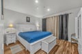Sink into your comfortable king-size bed with crisp linens and a cozy blue throw, surrounded by elegant white furnishings in this peaceful retreat.