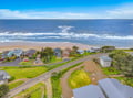 Aerial view of a charming beachfront neighborhood with direct sandy beach access and stunning oceanfront homes nestled along the coast.