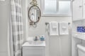 Freshen up in your bright bathroom with plush towels, nautical mirror, and cheerful striped shower curtain.