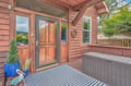 A warm wood-paneled entrance welcomes you to this charming retreat, featuring a covered porch, cheerful seasonal wreath, and convenient outdoor storage. Surrounded by lush greenery, this cozy entry feels like home.