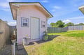 A charming standalone cottage set in a grassy backyard, offering privacy and a peaceful retreat. The soft pink siding and welcoming entrance create a cozy home base for your getaway.