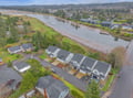 Aerial view showcasing the property's prime riverside location in a peaceful coastal community with scenic river and mountain surroundings.