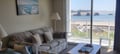 Picture yourself relaxing on the cozy sofa as you gaze at coastal rock formations through the glass doors. Natural light fills your living space, creating a peaceful retreat by the sea.