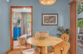 Enjoy your morning coffee at the charming wood table beneath a warm woven light fixture—your private dining nook awaits with serene blue walls and views of the lush greenery just outside.