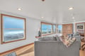 Relax in your comfortable living space with breathtaking ocean views through oversized windows that frame crashing waves and endless coastline.