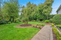 Beautifully landscaped garden with lush green lawn, mature trees, and thoughtfully designed planting beds creating a peaceful outdoor retreat.