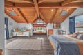 Relax under stunning exposed wooden beams in this spacious bedroom featuring multiple comfortable sleeping arrangements and charming rustic details.
