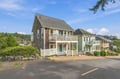 A charming coastal property featuring classic shingled architecture with white railings and balconies in a quiet neighborhood setting nestled among lush greenery.