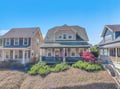 Charming coastal cottage with wraparound porch and American flag welcomes guests to this peaceful neighborhood retreat.