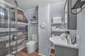 Freshen up in your stylish bathroom featuring a glass shower, modern fixtures, and thoughtfully stocked shelves with fluffy towels.