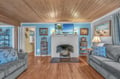 Cozy up in this charming living room with wood-beam ceilings, a crackling fireplace, and comfortable seating for your perfect coastal retreat.