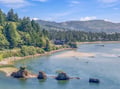 An aerial view of the property's scenic waterfront location, nestled along a tranquil river with mountain backdrop and lush forested surroundings.