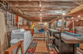 Your basement game room offers pool, cozy seating, and convenient laundry facilities under rustic exposed beams.