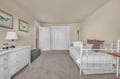 Sink into your cozy bedroom with plush carpeting, white iron bed, and peaceful nautical artwork creating the perfect retreat for restful nights.