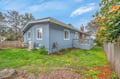 Charming blue cottage with spacious yard, perfect for outdoor relaxation and surrounded by mature trees and blooming flowers.