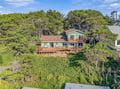 Nestled among coastal trees, this charming retreat offers spacious decks and a serene, natural setting perfect for a peaceful getaway.