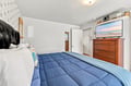 Settle into your cozy bedroom with crisp linens, a plush comforter, and coastal charm. The TV awaits your favorite shows while warm wood furnishings add a welcoming touch.
