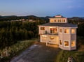 Modern coastal retreat with panoramic mountain views and spacious decks, nestled among rolling hills and forest landscapes.