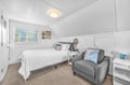 Your cozy attic bedroom features crisp white linens and a comfy reading chair, perfect for unwinding after coastal adventures.