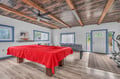 Your game room awaits with pool table, foosball, and exercise equipment under stunning reclaimed wood ceilings.