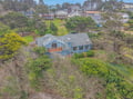 Charming coastal home nestled among lush trees and rolling hills in a peaceful residential neighborhood.