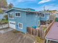 Charming blue coastal home with deck and garage in peaceful residential neighborhood.