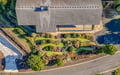 Aerial view captures the property's impressive landscaped gardens featuring winding pathways through colorful flower beds and manicured lawns.